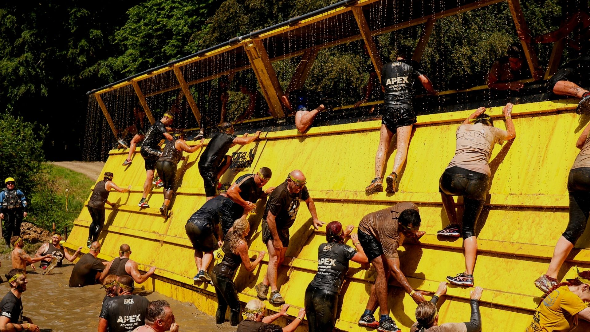 Competitors climb a high wall