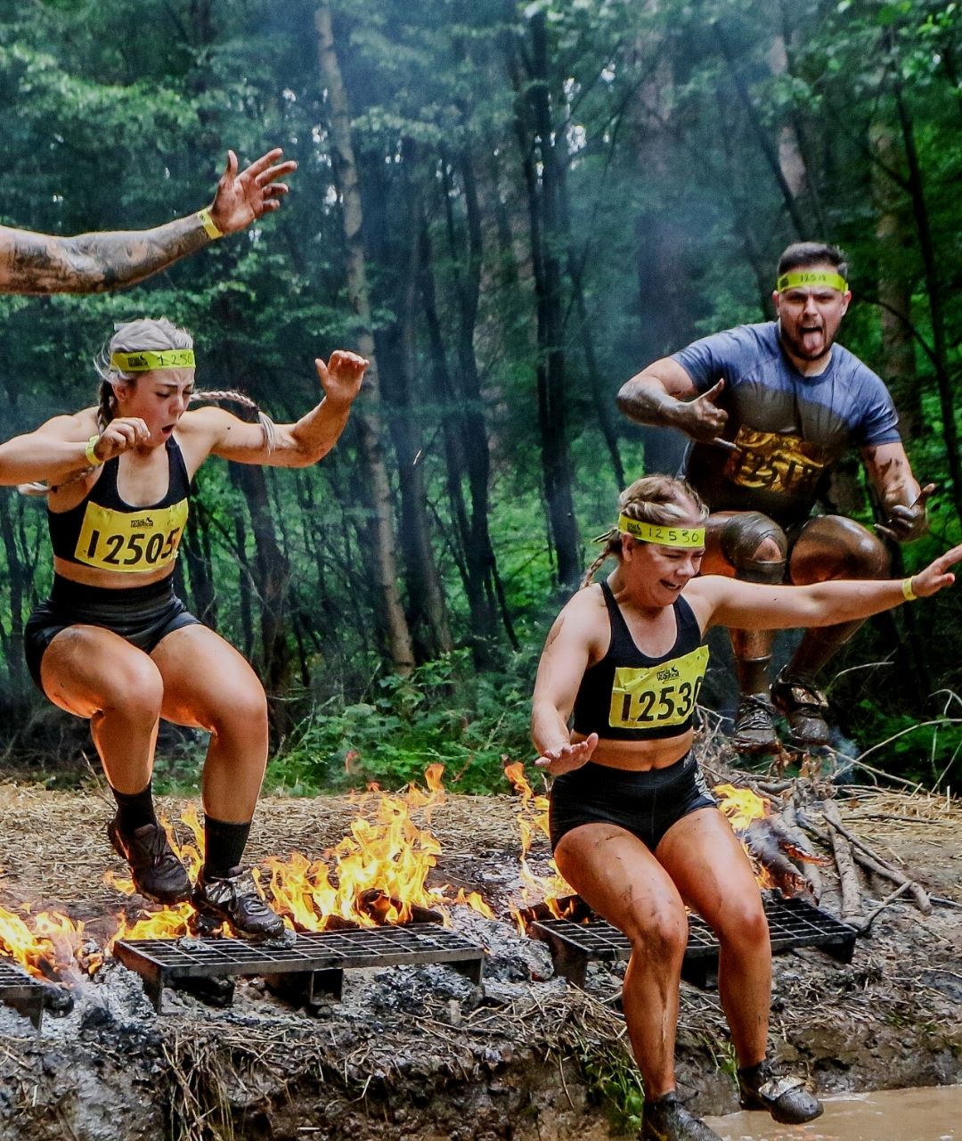 Competitors jump over fire into mud